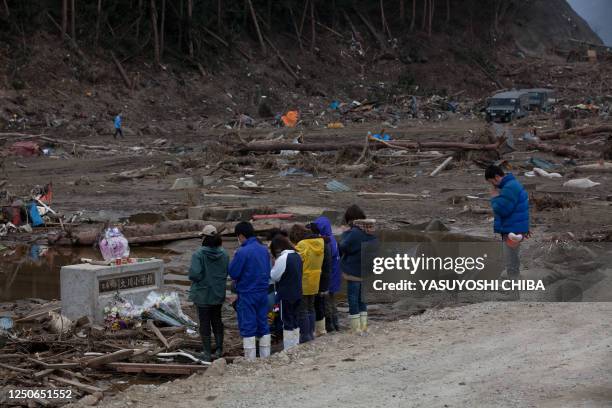 Month after the tsunami divastation, parents, who lost their children at the Okawa elementary school, pray at the gate where only the name plate...