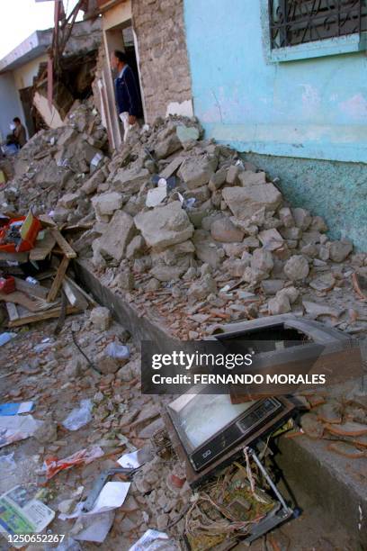 Villager stands on his house doorway behind destroyed objects in Cojutepeque, 35 km east from San Salvador, El Salvador, 14 February 2001. Un...