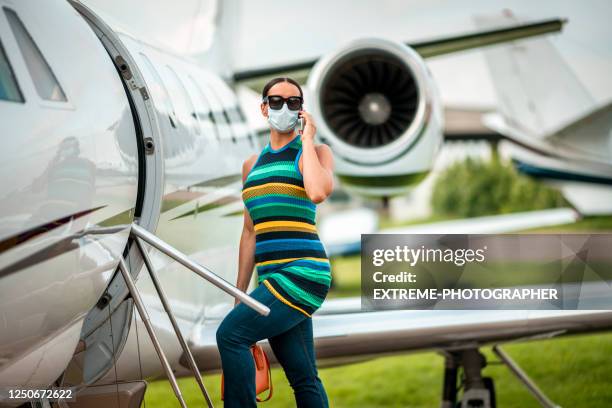 a female boarding a private jet with a face mask and sunglasses on, talking on a mobile phone - billionaire stock pictures, royalty-free photos & images