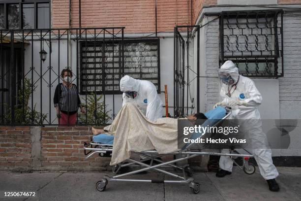 Paramedics of the Mexican Red Cross transfer on a stretcher a person with possible COVID-19 to an ambulance during the answer to an emergency call on...