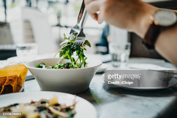 cropped shot of a woman's hand serving healthy salad on plate while having lunch in a restaurant - leaf vegetable stock pictures, royalty-free photos & images