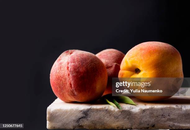 ripe peaches on a stone marble table. dark background, low key. creative art photo with fruits. - nectarine photos et images de collection