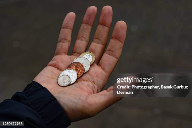 a man's hand holding british coins - coin stock pictures, royalty-free photos & images