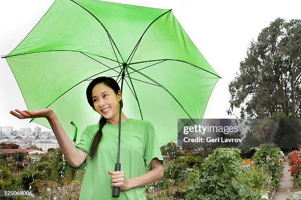 asian woman standing in rain using umbrella - women in wet tee shirts stock pictures, royalty-free photos & images