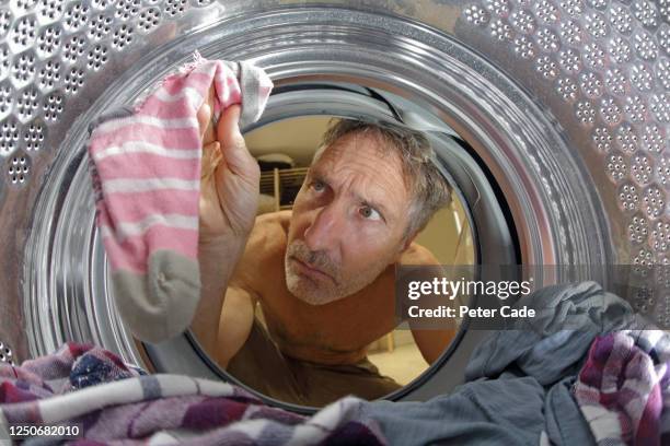 man looking into washing machine at laundry - lost sock stock pictures, royalty-free photos & images