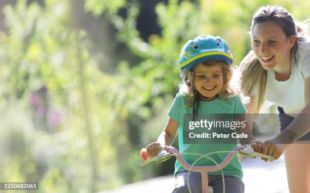 mother teaching daughter to ride a bike - bicycle safety light stockfoto's en -beelden