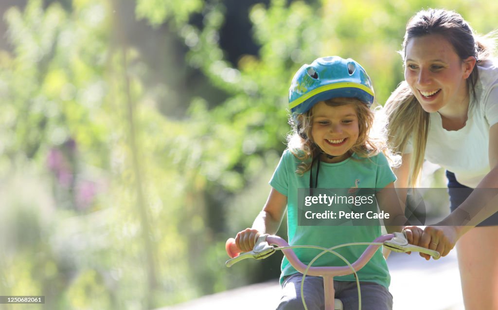 Mother teaching daughter to ride a bike