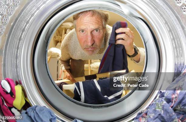 older man doing the laundry, looking into washing machine - washing machine front stock pictures, royalty-free photos & images