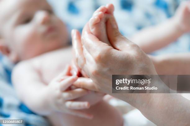 mother makes foot massage for her baby - reflexology stock-fotos und bilder