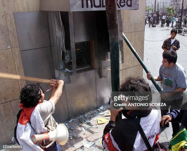 Demonstrators destroy an electronic teller machine in Lima, Peru 25 May, 2000 during a protest ahead of the 28 May presidential run off election....