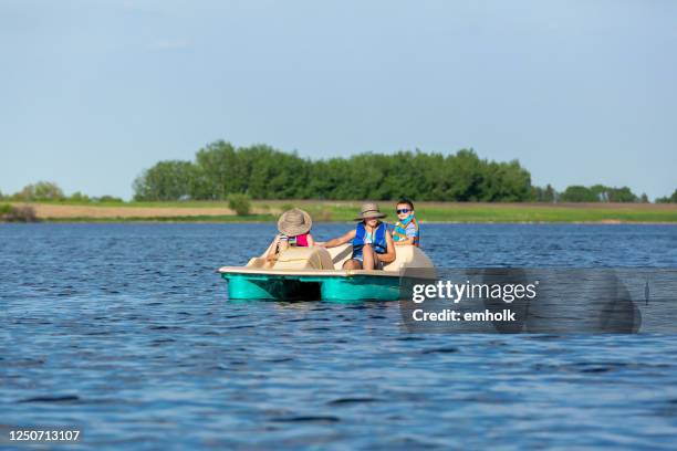 tre bambini in pedalò sull'acqua del lago - battello-con-ruota-a-pale foto e immagini stock