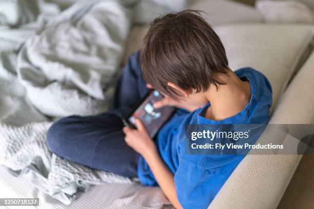 nine-year old ethnic boy plays game on phone - screen time stock pictures, royalty-free photos & images