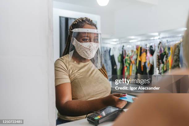 glimlachende winkelier die gezichtsschild in pandemie gebruikt - business woman schild stockfoto's en -beelden