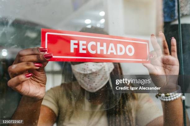 bankruptcy: woman hanging closed notice in store - brazil covid stock pictures, royalty-free photos & images