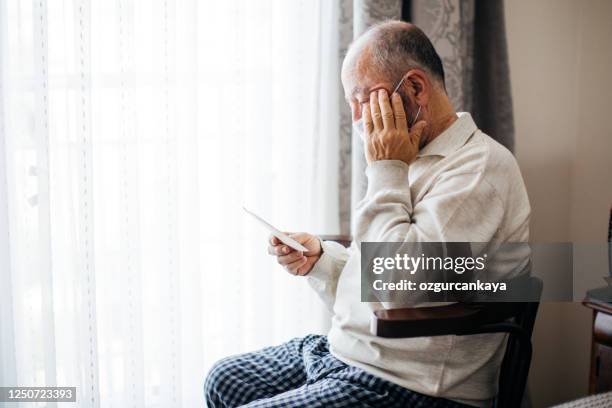 hombre mayor mirando marco de fotos - viudo fotografías e imágenes de stock