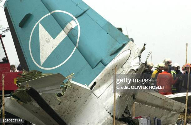 Firemen and rescuers stand near the tail of a Fokker 50 plane of Luxembourg's Luxair airline in Niederanven 06 November 2002. At least 17 people died...