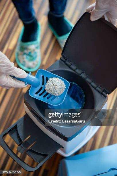 high angle view of pet owner disposing dirty cat sand into garbage bin with shovel - stock photo - cat litter stock pictures, royalty-free photos & images