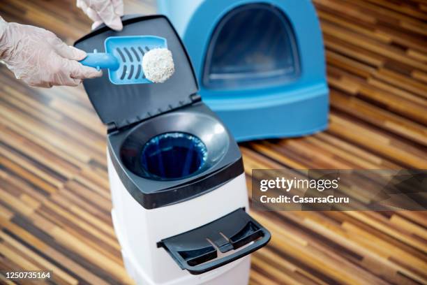 frau hände in chirurgischehandschuhe mit schaufel, um klumpen von katzensand in katze wurf entsorgung behälter werfen - stock-foto - handschuh stock-fotos und bilder