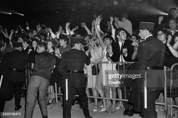 Policemen contain French fans waiting for the Beatles before their concert at the Palais des Sports in Paris, on June 20, 1965. - British band The...