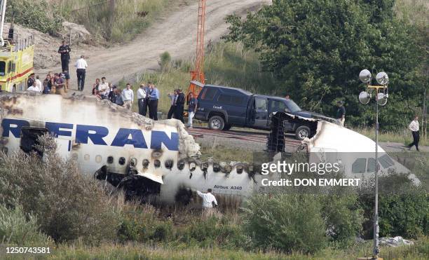 Officials view the wreckage of the Air France Airbus A340 at Toronto's Pearson International Airport 03 August 2005, one day after it skid off the...