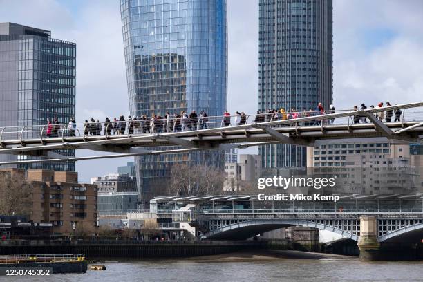 People crossing the River Thames at Millennium Bridge towards One Blackfriars and Kings Reach Tower on 30th March 2023 in London, United Kingdom. The...