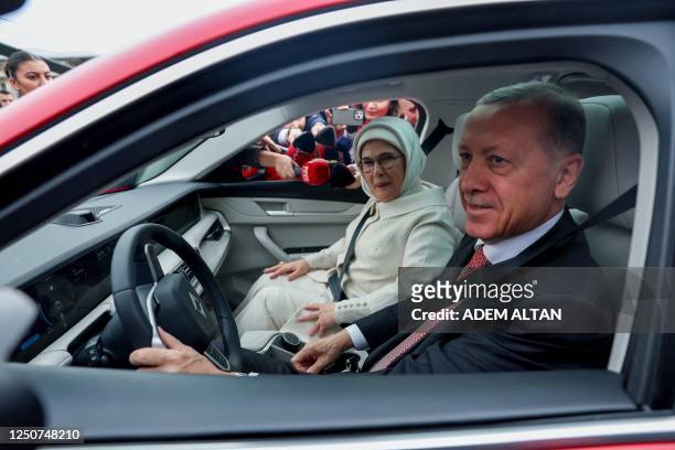 Turkey's President Recep Tayyip Erdogan and his wife Emine Erdogan sit in their Togg T10X, Turkey's first domestically-produced electric car, after...