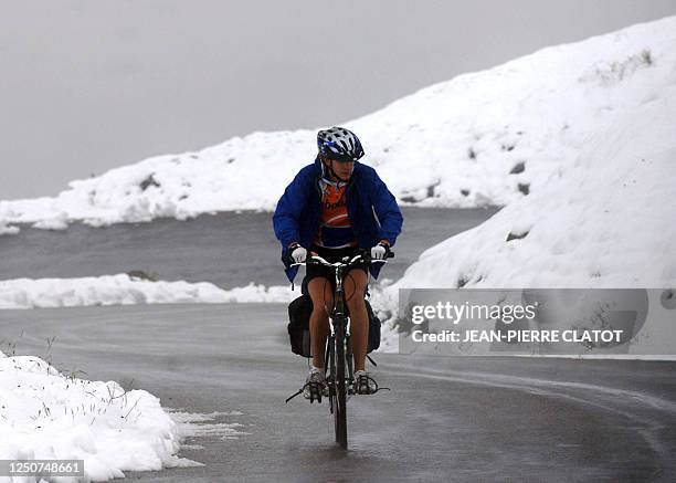 Cyclist climbs the Iseran gap as snow covered the mountain, 09 August 2007 in Val-d'Isere, French Alps.