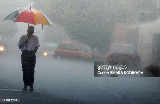 Sri Lankan man walks through heavy rain along a street in Colombo on May 14, 2010. The capital city was lashed by heavy rains causing majot traffic...