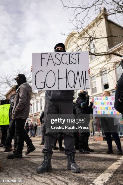 An anti-fascist counter-protester holds a sign outside the entrance of Element 41, a restaurant holding an 18 and over drag brunch to raise money for...