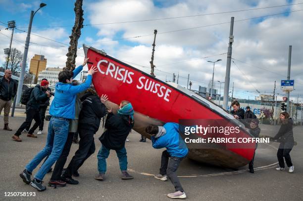 Climate activists raise a boat during a protest ahead of the annual general meeting of Credit Suisse bank, in Zurich, on April 4 following the...