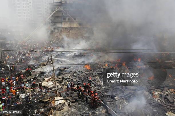 Firefighters and local people try to extinguish a fire that broke out in a clothing market in Dhaka, Bangladesh on April 4, 2023. 48 units of the...