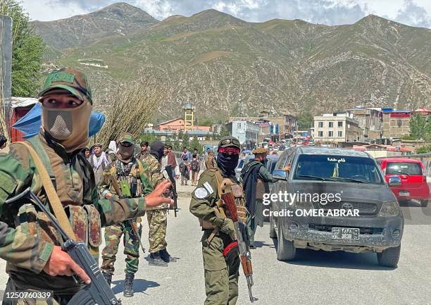 Taliban security personnel stand guard along a street to remove the window tint films from the cars of the commuters at a checkpoint in Fayzabad...