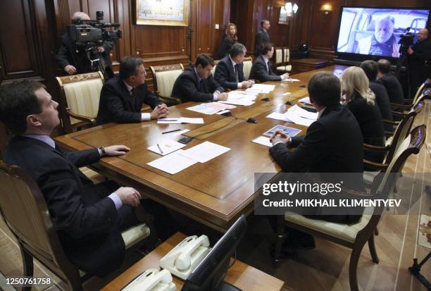 Russian President Dmitry Medvedev participates in a video conference with emergency workers at the scene of a passenger train disaster, from outside...