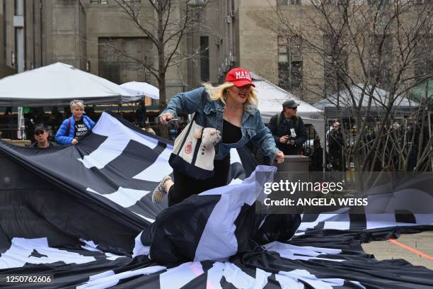 Supporter of former US President Donals Trump tears up a banner from anti trump supporters during a protest outside of Manhattan Criminal Court in...