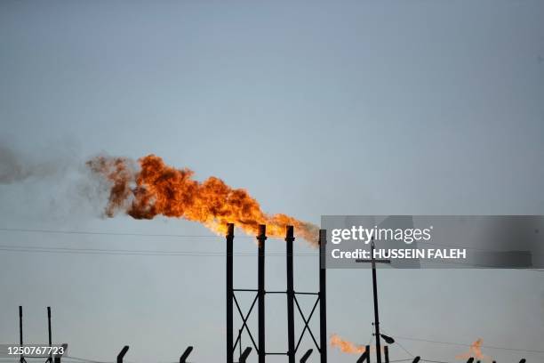 Flare stacks burn in the Nahr Bin Omar oil field and facility near Iraq's southern port city of Basra on April 4, 2023. - Major oil powers led by...