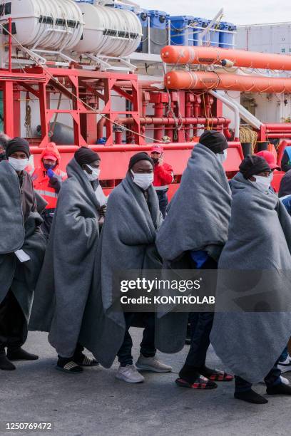 Migrants in line wrapped in blankets just landed from the NGO SOS Mediterranean Ocean Viking ship that rescued 92 people, including nine women and 40...