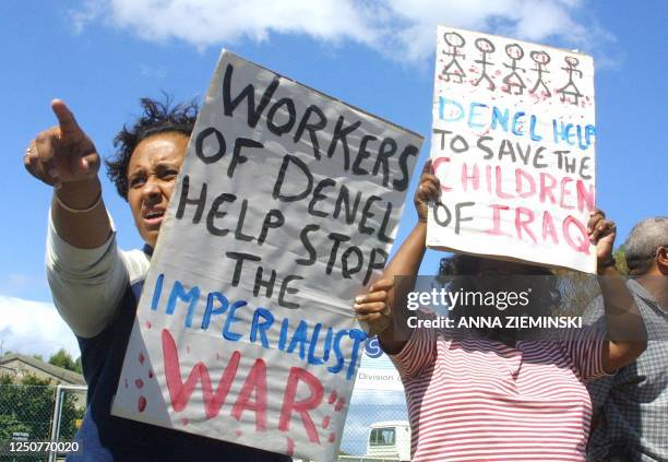 Anti-war protestors hold up placards as tens of protesters picketed outside the Swartklips explosives factory, a division of the Denel armaments...
