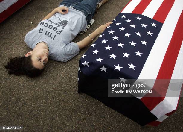 Anti-war activist Angela Kelly of Peace Action rests her hand on a flag-draped coffin representing the soldiers that have died in Iraq during a...