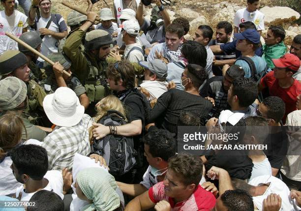 Palestinians and peace activists scuffle with Israeli soldiers during a protest against the construction of part of Israel's separation barrier in...