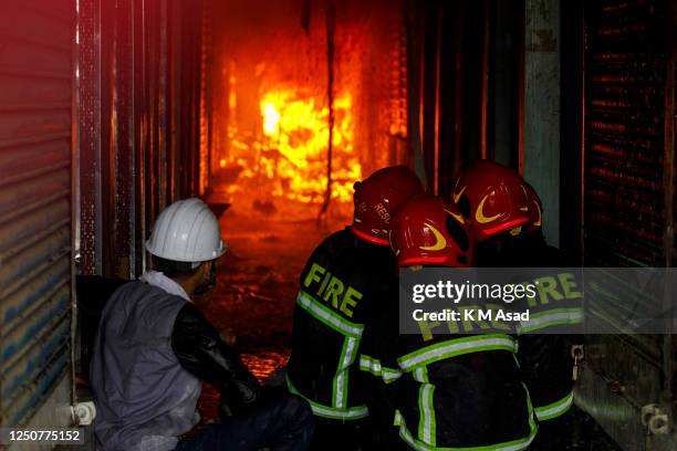 Bangladeshi firefighters trying to extinguish a fire that broke out at Bangabazar clothing market in Dhaka. Thousands of clothes shops burn down in...