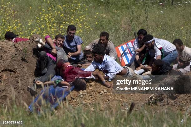 Demonstrators prepare to evacuate a wounded fellow protestor who was hit by Israeli forces fire while trying to cut through a line of barbed wire and...