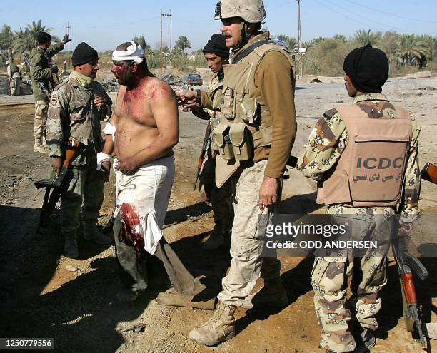 Marine and Iraqi soldiers assist a wounded Iraqi civilian to an Ambulance after a suicide bomber blew himself and his veichle up at an Iraqi national...