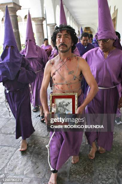 Penitentes, encabezados por un hombre atado con alambre de puas, salen de la Iglesia de San Francisco en Quito, durante la procesion de Jesus del...