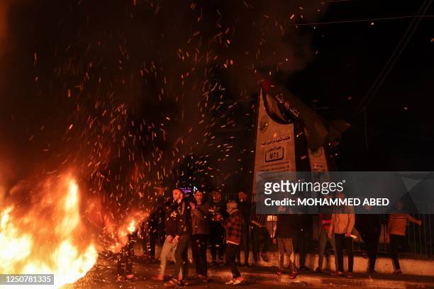 Palestinian youth react as they burn tires during a protest on the streets of Gaza City on April 5, 2023. - Clashes erupted inside the Al-Aqsa mosque...