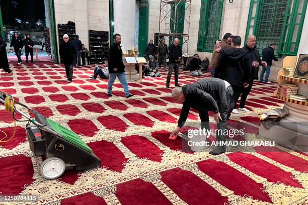 Men clean the Al-Aqsa mosque in Jerusalem's Old City following clashes between Palestinian worshippers and Israeli security forces early on April 5...