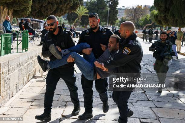 Israeli policemen detain a Palestinian man at the Al-Aqsa Mosque compound following clashes that erupted during the Islamic holy fasting month of...