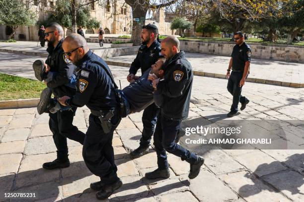 Israeli policemen detain a Palestinian man at the Al-Aqsa Mosque compound following clashes that erupted during the Islamic holy fasting month of...