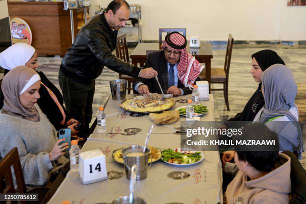 Tamer Majal , co-owner co-owner of a traditional restaurant, serves a dish of "Mansaf" to Jordanian writer and researcher Hasan Mubaydin and other...