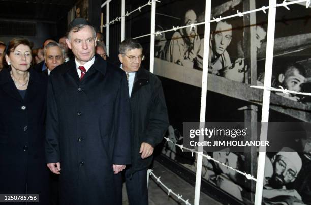 German President Horst Koehler, flanked by his wife Eva and a guide to the Yad Vashem Holocaust Memorial, passes a photo mural from a Nazi death camp...