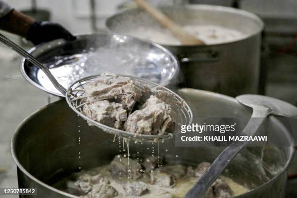 Cook prepares a pot of the traditional Jordanian dish "Mansaf" at a restaurant kitchen in Amman on March 16, 2023. - The kingdom's national dish was...